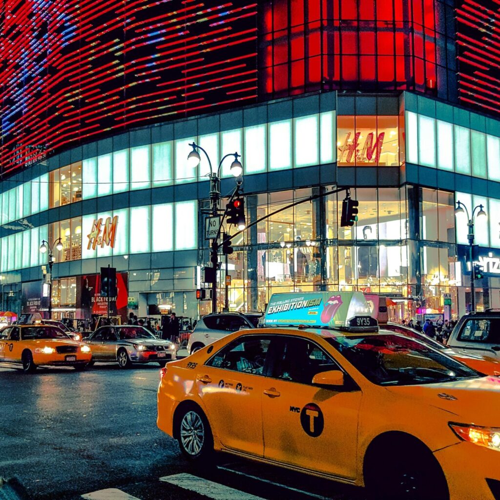 Dynamic night scene in Times Square with traffic and illuminated buildings.