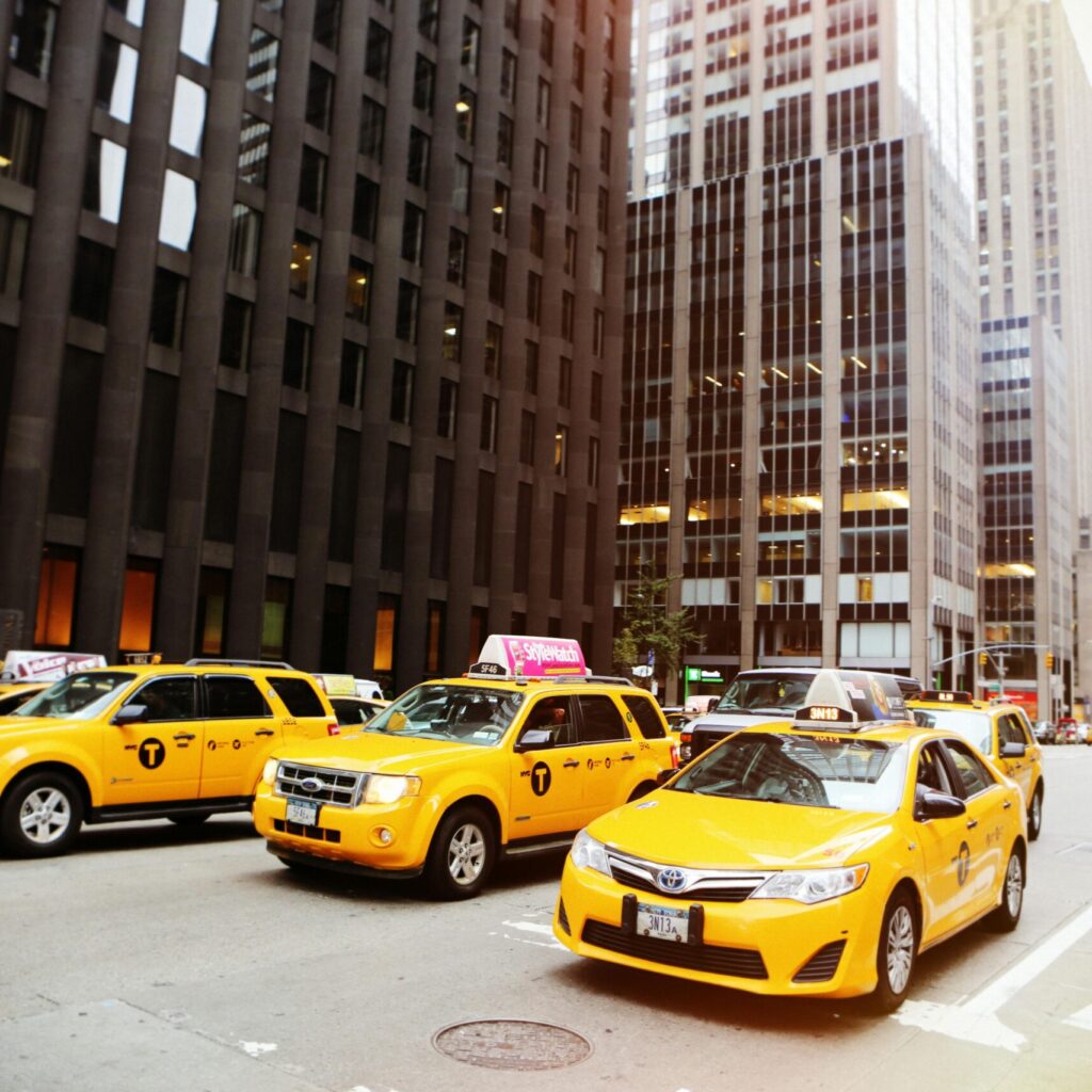 Street scene with yellow taxis in New York City, iconic urban traffic captured in daylight.